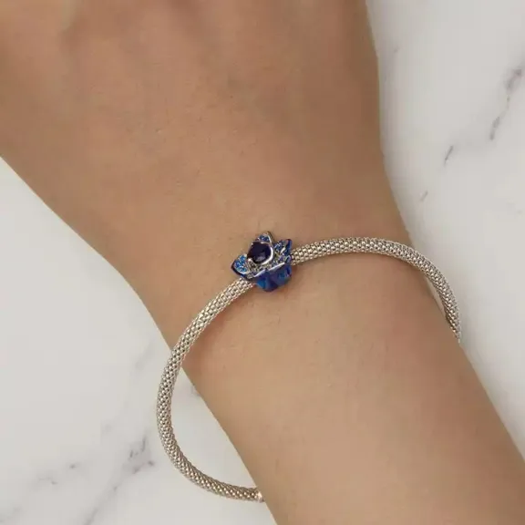JBX CHARM BLUE FLOWER SILVER PÅ ET ARMBÅND PÅ EN MODELLS HÅNDLEDD